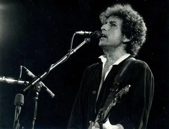 Bob Dylan at microphone playing guitar