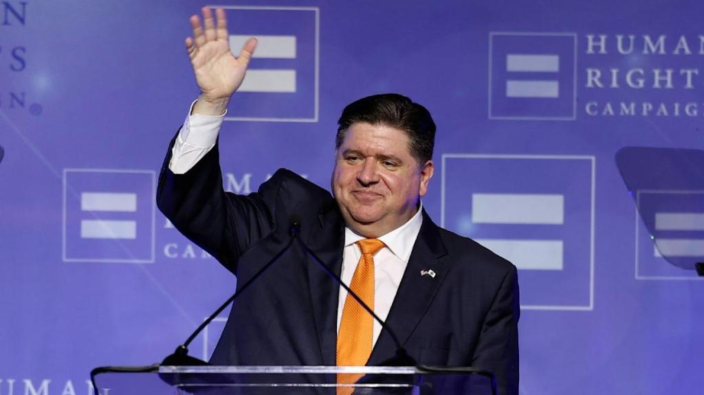 Illinois Governor JB Pritzker at podium waving to crowd