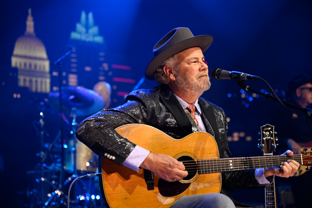 Singer Robert Earl Keen sitting and playing a guitar