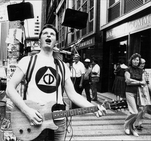 Billy Bragg outside on stairs playing electric guitar