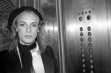 Brian Eno circal 1978 in an elevator in front of button panel