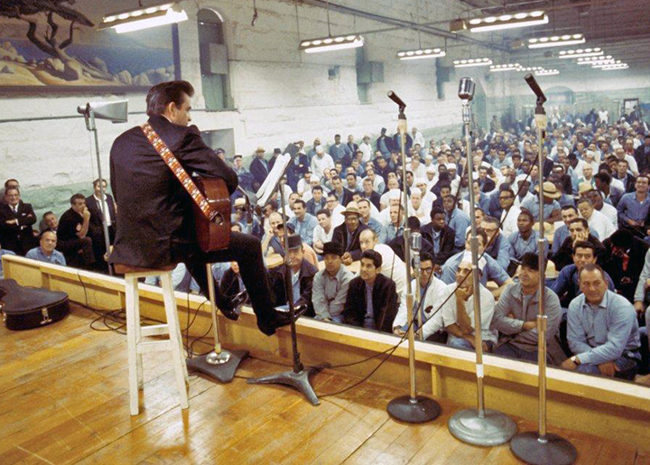 Johnny Cash on stool with guitar playing at Folsom Prison