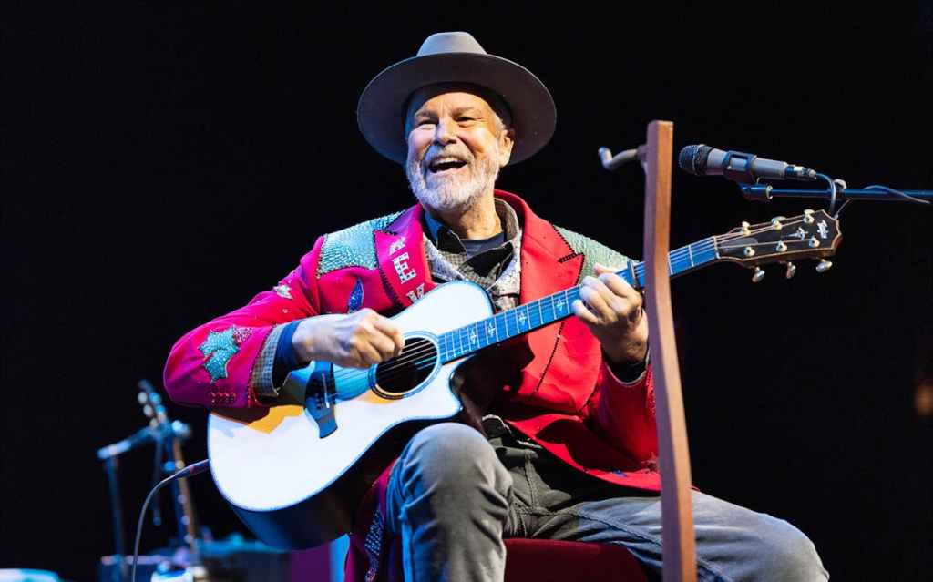 Robert Earl Keen sitting and playiing acoustic guitar