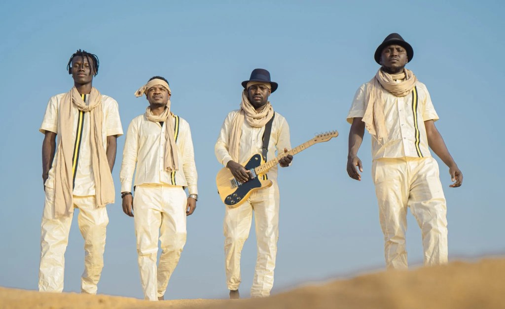 The band Songhoy Blues standing in front of blue skies.