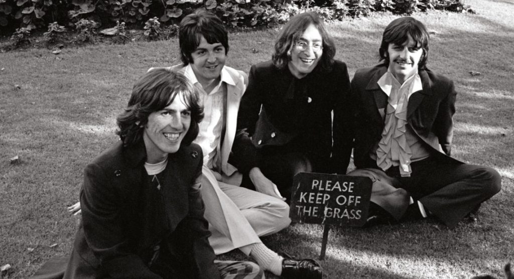 Group shot of The Beatles seated on the ground - 1968