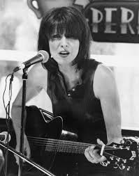 Chrissie Hynde sitting at microphone with guitar