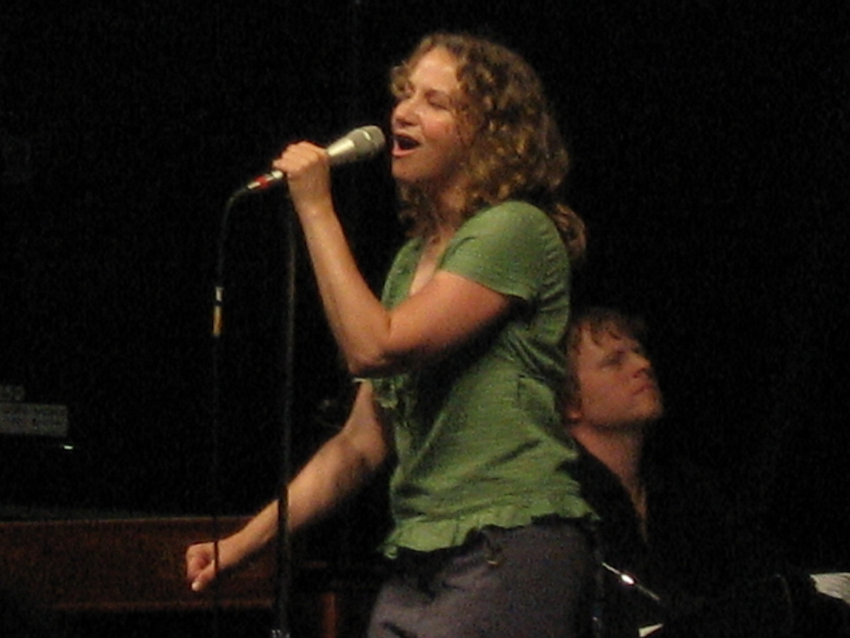 Singer Joan Osborne on stage holding microphone and singing