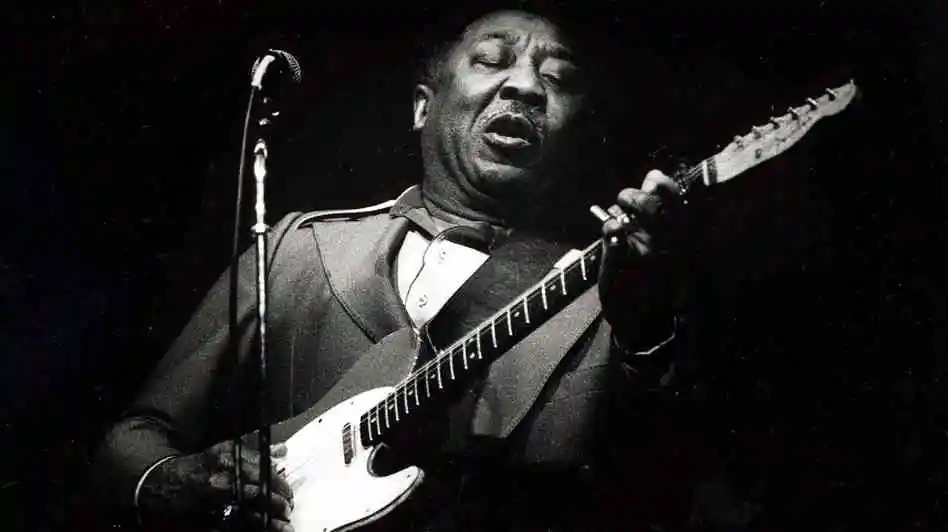Chicago Blues musician Muddy Waters playing electric guitar in front of microphone