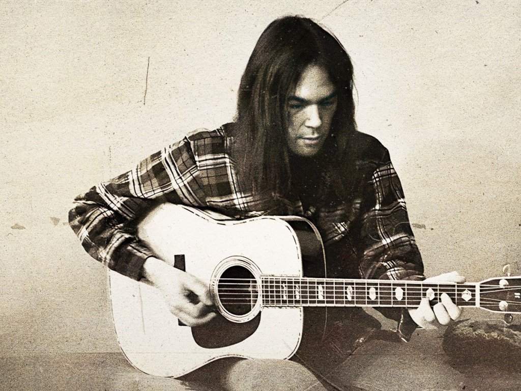 Neil Young seated with acoustic guitar