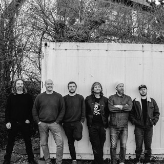 Th Bees group shot - outdoors in front of white wall