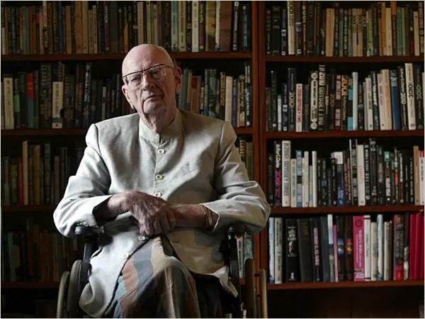 Science Fiction author Arthur C. Clarke seated in front of a wall full of books