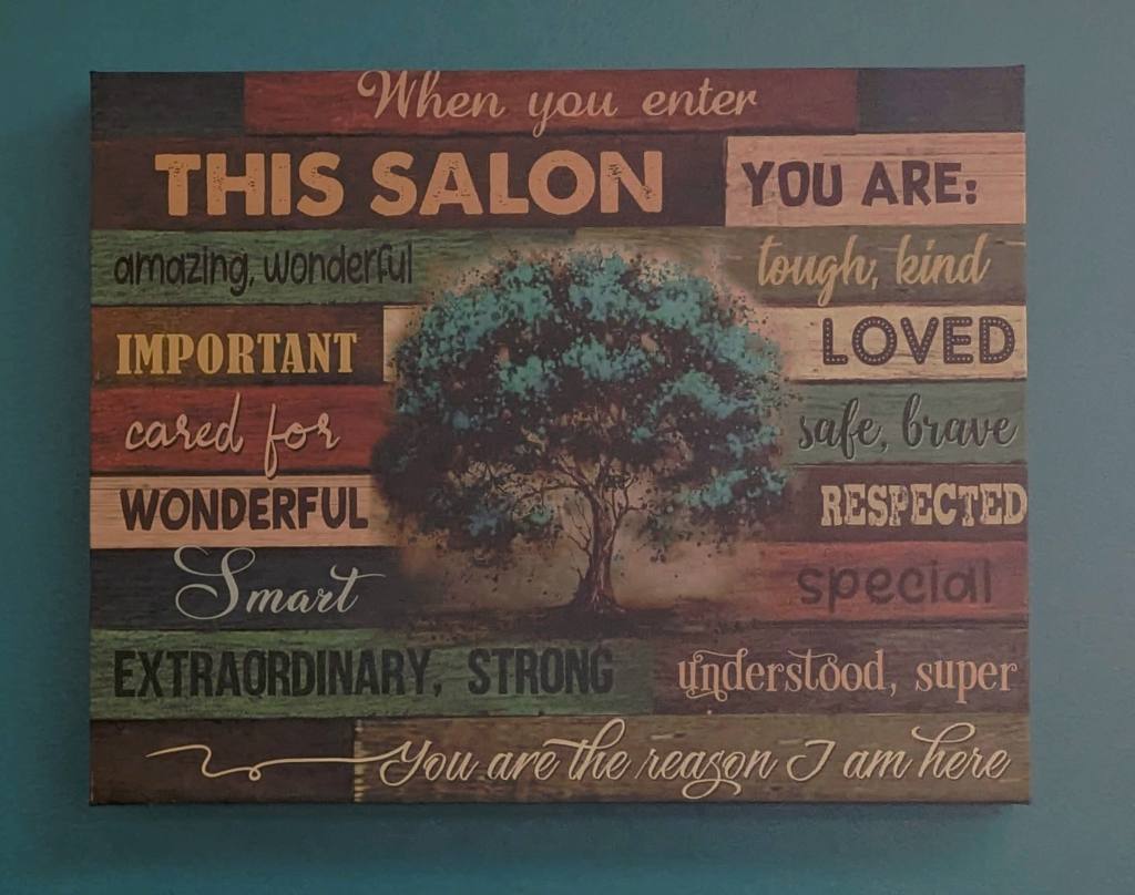 A piece of art with words surrounding a tree in the middle. The words vary in style and color but say "When you enter THIS SALON YOU ARE: amazing, wonderful tough, kind IMPORTANT LOVED cared for safe, brave WONDERFUL RESPECTED Smart special EXTRAORDINARY, STRONG understood, super You are the reason I am here.