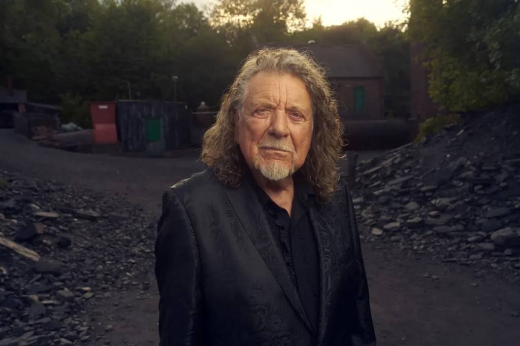 Singer Robert Plant standing outdoors wearing black shirt and jacket