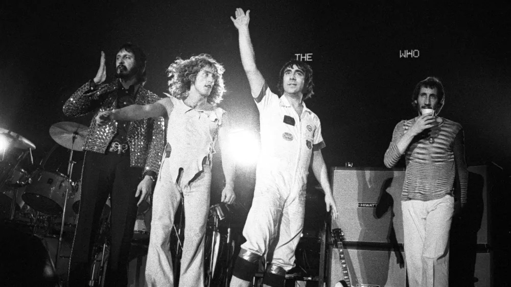 Photo of The Who standing at front of stage