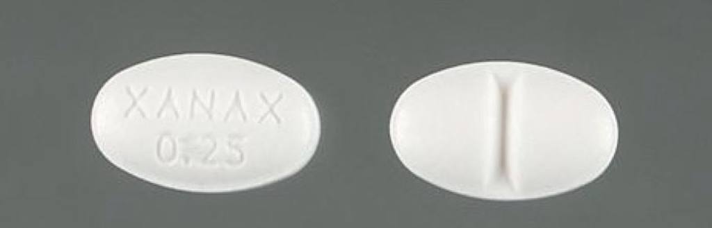 Photo of two white oval pills, one of which is labeled Xanax
