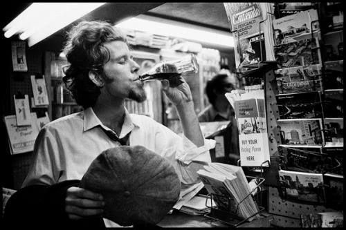 1973 photo of Tom Waits sitting in book store drinking from a bottle - photo by Scott Smith