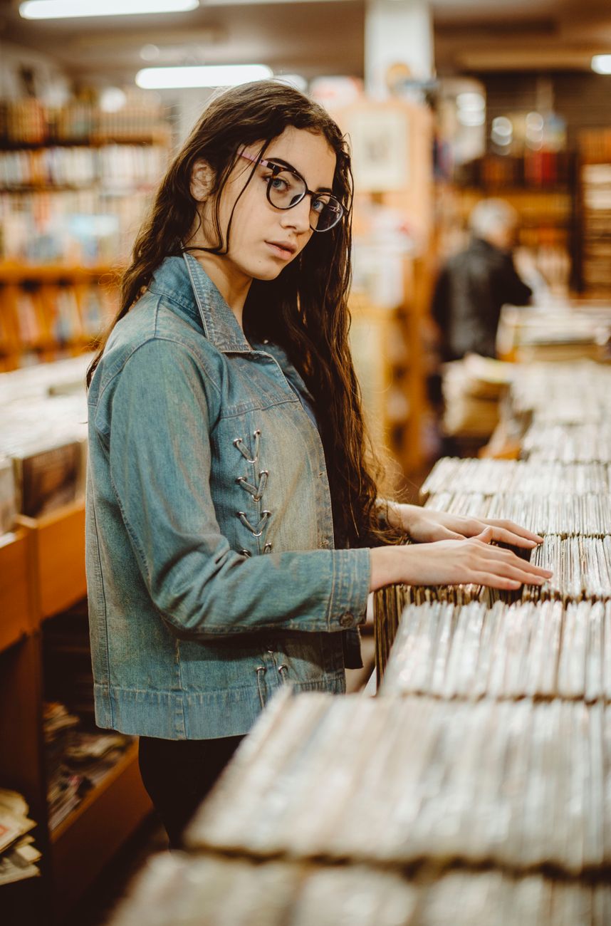 brunette wearing eyeglasses in store with vinyl record